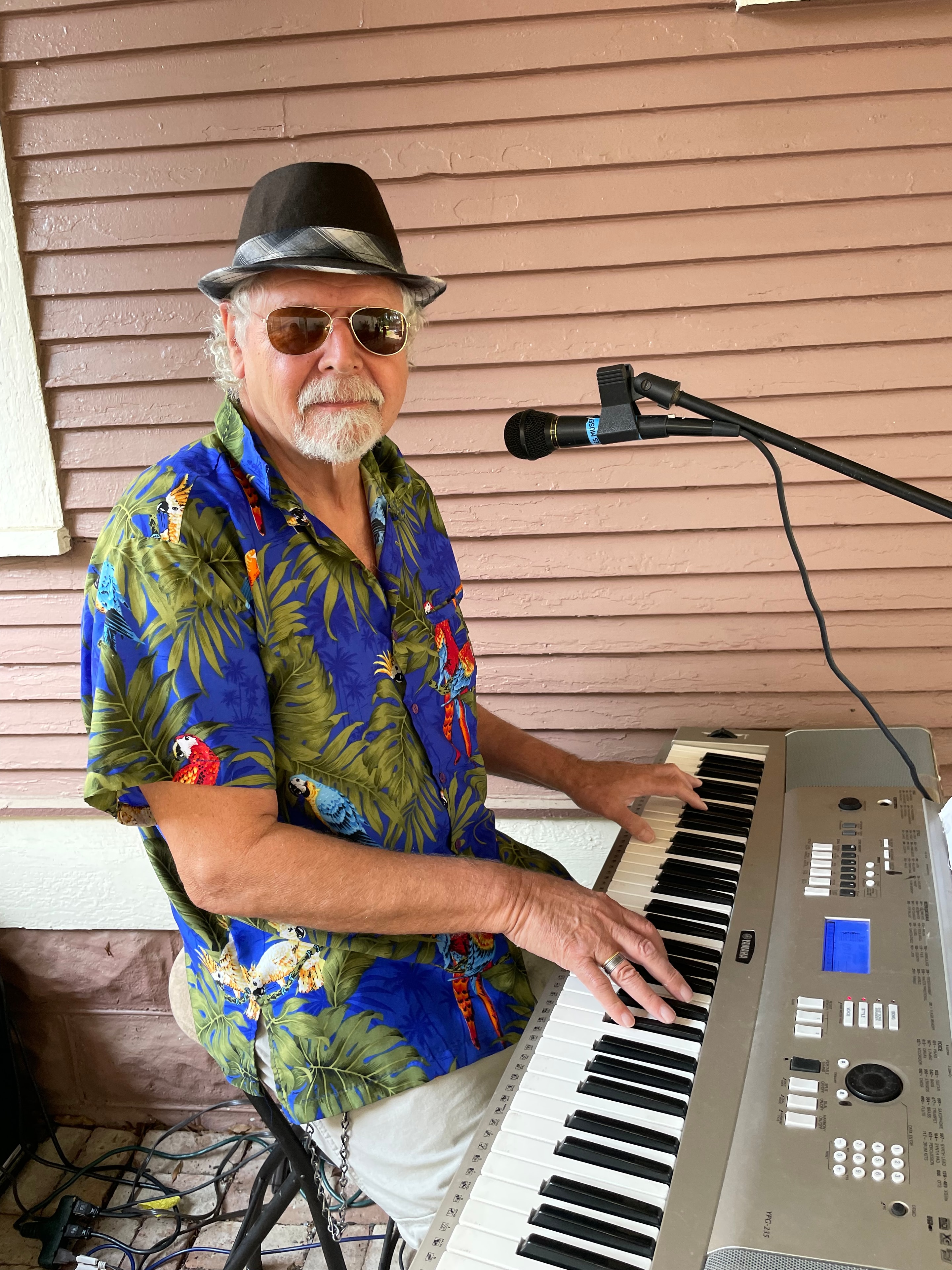 Musician playing keyboard outdoors wearing a blue Hawaiian shirt
